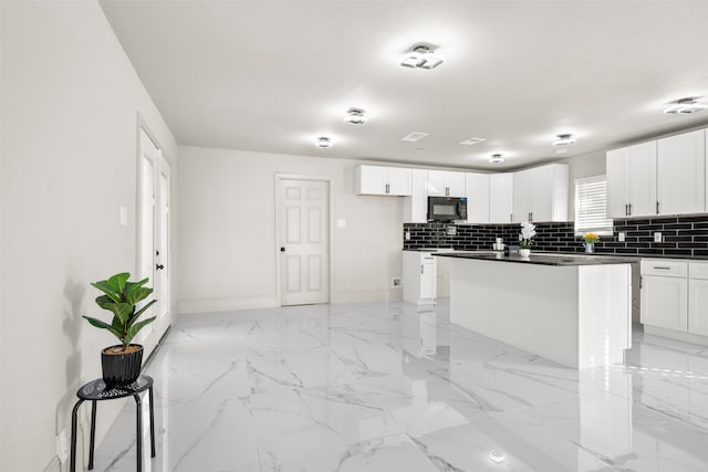 kitchen with white cabinets, a kitchen island, and backsplash