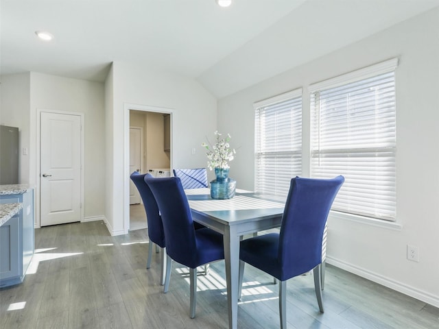 dining room featuring vaulted ceiling and light wood-type flooring