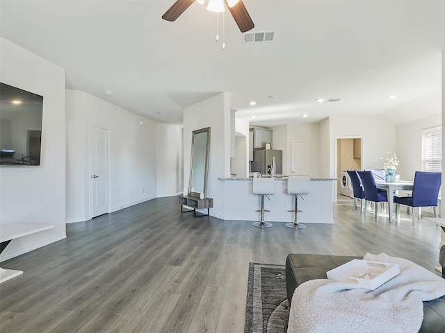 living room featuring ceiling fan and dark hardwood / wood-style floors