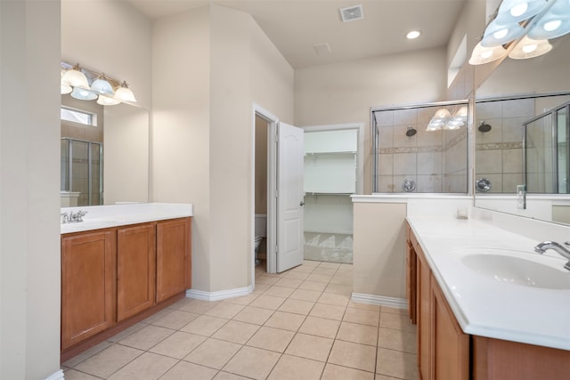 bathroom with tile patterned floors, vanity, a shower with shower door, and toilet