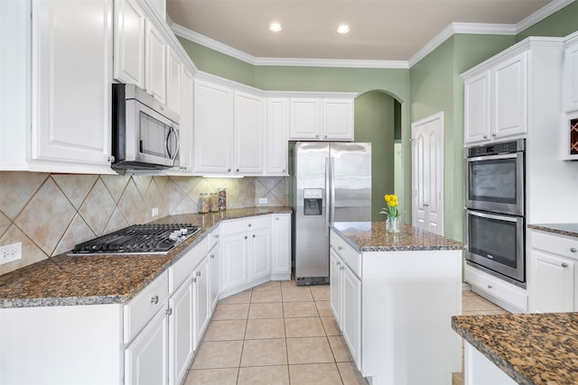 kitchen featuring appliances with stainless steel finishes, tasteful backsplash, a kitchen island, crown molding, and white cabinetry