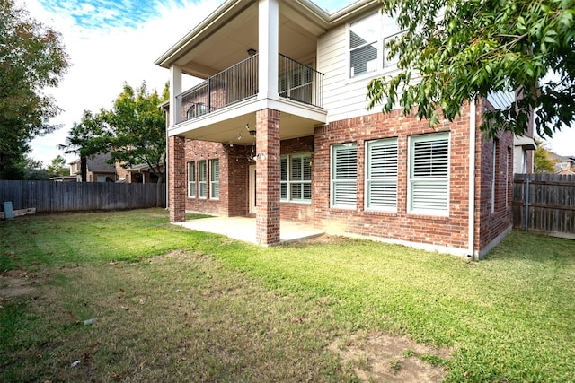 rear view of property with a yard, a balcony, and a patio