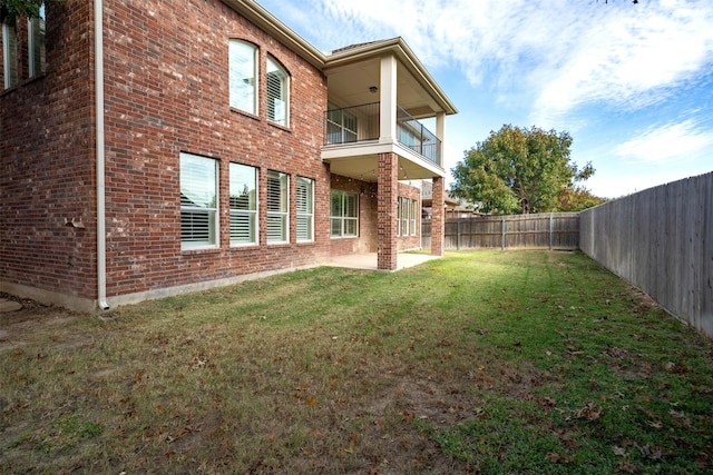 back of house with a balcony and a yard