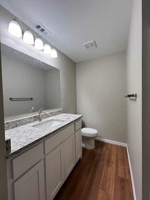 bathroom with vanity, toilet, wood-type flooring, and a textured ceiling