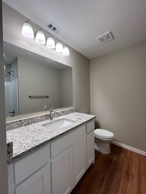 bathroom featuring vanity, hardwood / wood-style flooring, toilet, walk in shower, and a textured ceiling