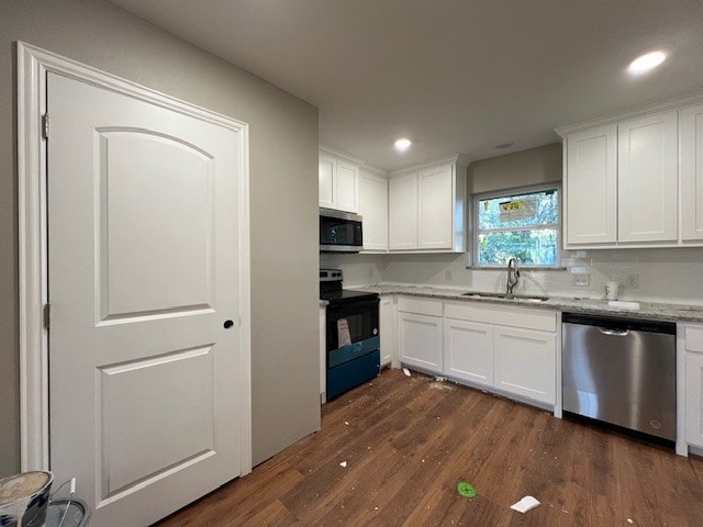 kitchen with sink, appliances with stainless steel finishes, white cabinetry, dark hardwood / wood-style floors, and light stone countertops