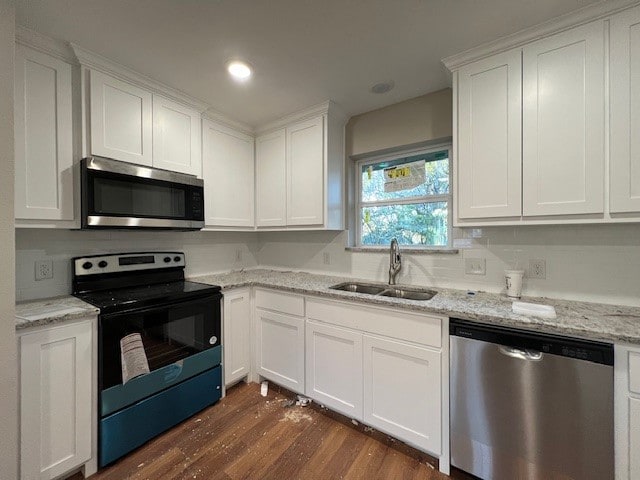 kitchen with light stone countertops, white cabinetry, sink, dark wood-type flooring, and stainless steel appliances