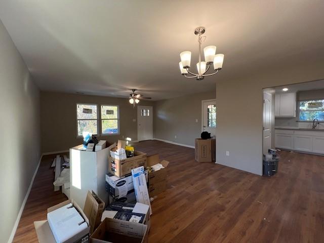 living room with ceiling fan with notable chandelier, dark hardwood / wood-style floors, and sink