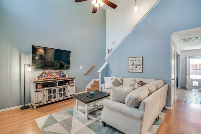 living room with a high ceiling, light hardwood / wood-style flooring, and ceiling fan