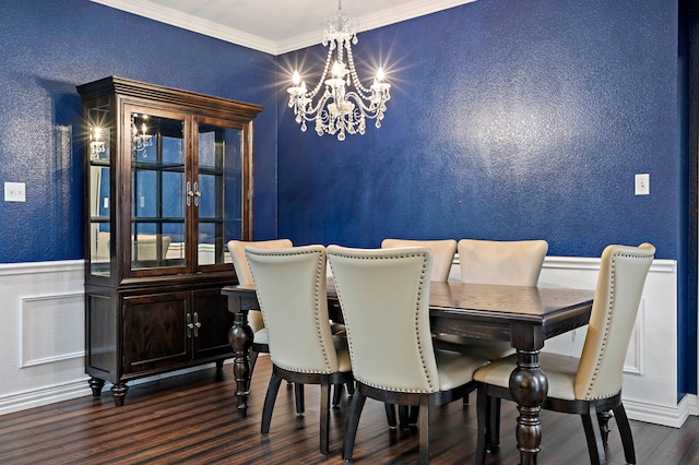 dining space with a wainscoted wall, dark wood-type flooring, ornamental molding, a chandelier, and a textured wall