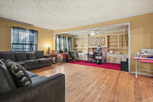 living room with ceiling fan, wood-type flooring, built in features, and a textured ceiling