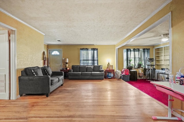 living room featuring hardwood / wood-style flooring, crown molding, built in shelves, and a textured ceiling