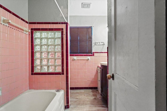 bathroom with tile walls, vanity, a bathtub, and hardwood / wood-style flooring