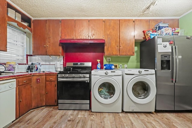 kitchen featuring appliances with stainless steel finishes, independent washer and dryer, light hardwood / wood-style floors, a textured ceiling, and decorative backsplash