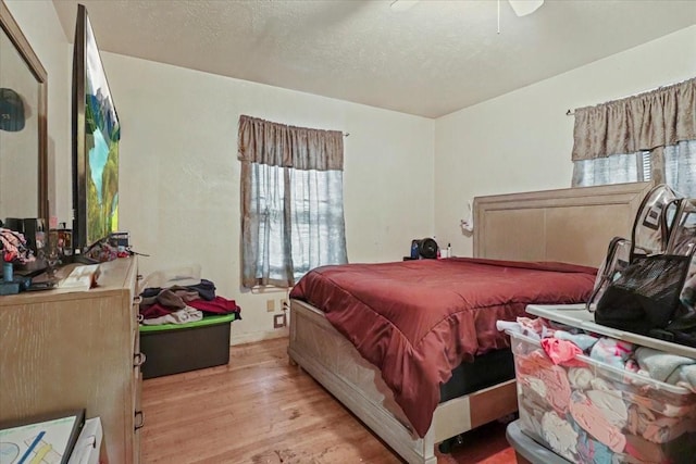 bedroom featuring ceiling fan, light hardwood / wood-style flooring, and a textured ceiling