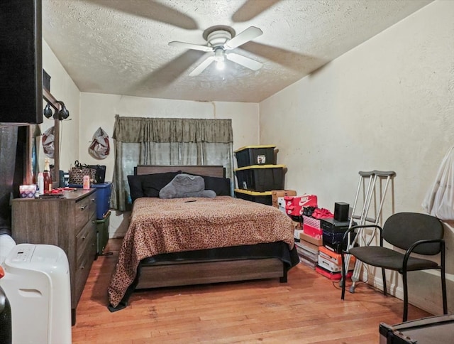 bedroom featuring ceiling fan, a textured ceiling, and light wood-type flooring