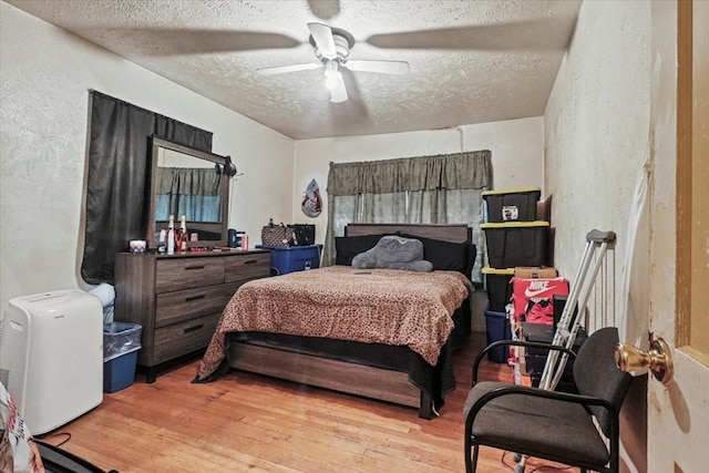 bedroom featuring ceiling fan, a textured ceiling, and light wood-type flooring