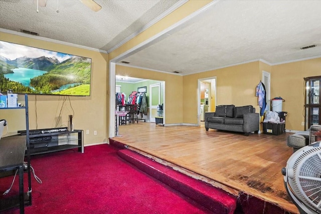 living room featuring hardwood / wood-style flooring, ornamental molding, ceiling fan, and a textured ceiling