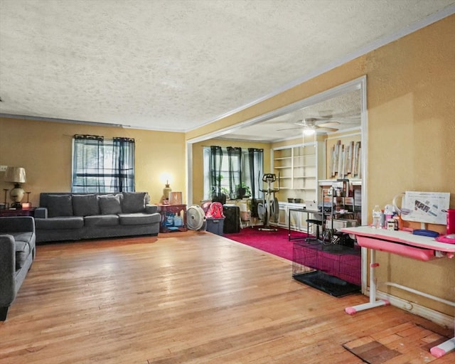 living room with hardwood / wood-style flooring, built in features, ceiling fan, ornamental molding, and a textured ceiling