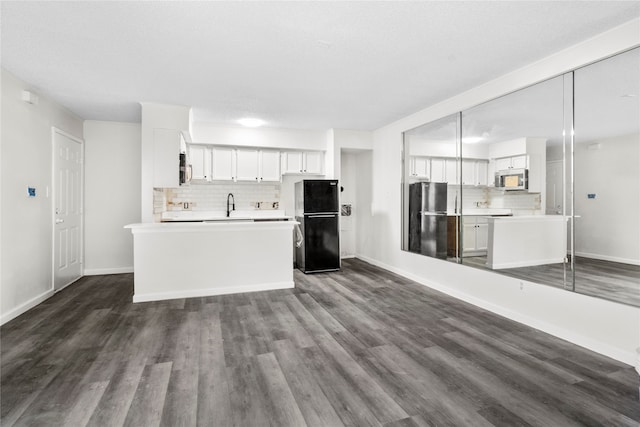 kitchen with dark hardwood / wood-style flooring, backsplash, stainless steel appliances, a kitchen island, and white cabinetry