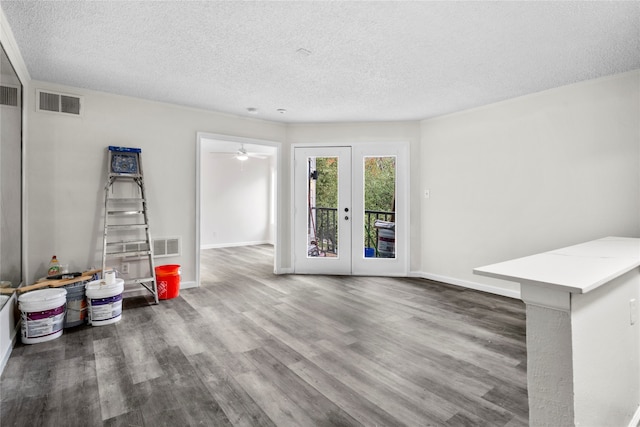 unfurnished living room featuring french doors, a textured ceiling, and dark wood-type flooring