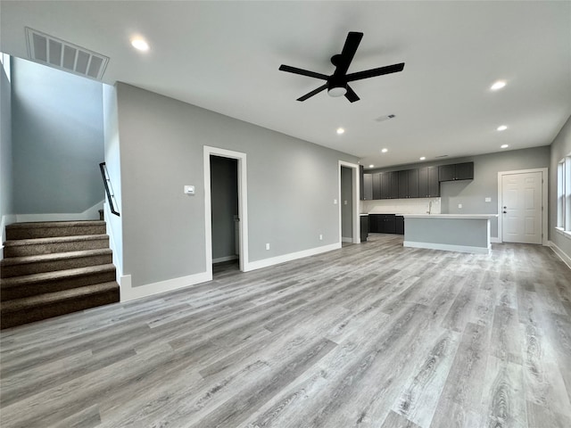 unfurnished living room with ceiling fan, sink, and light hardwood / wood-style floors