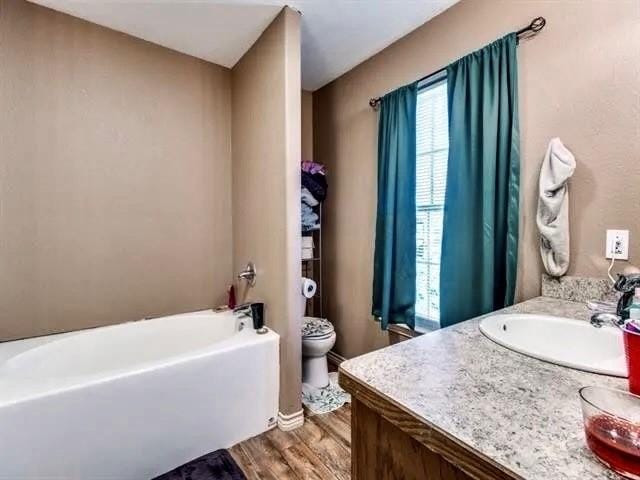 bathroom with vanity, toilet, hardwood / wood-style floors, and a bath