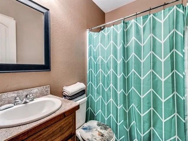 bathroom featuring walk in shower, vanity, and toilet