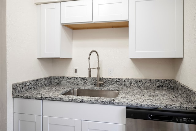 kitchen featuring light stone counters, dishwasher, white cabinets, and sink