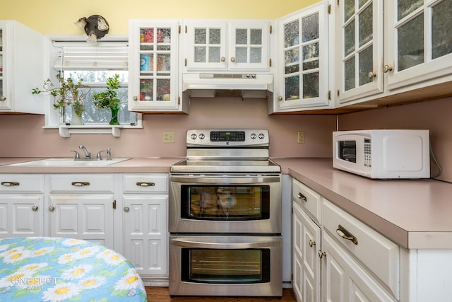 kitchen featuring light countertops, range with two ovens, white cabinets, and under cabinet range hood