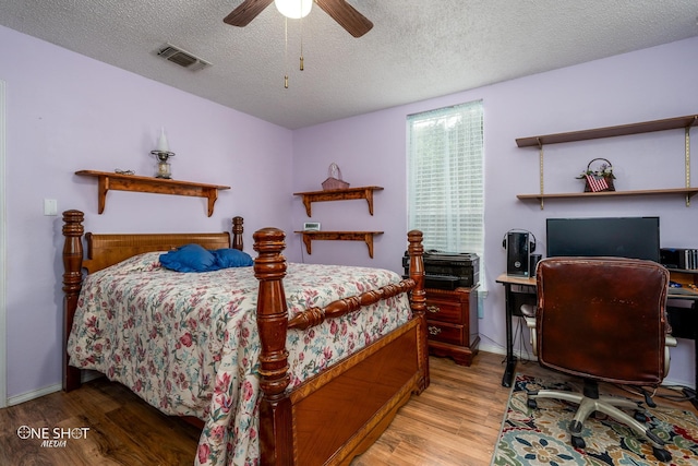 bedroom featuring visible vents, light wood-style floors, a ceiling fan, a textured ceiling, and baseboards