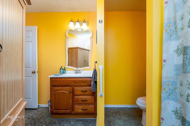 bathroom with baseboards, vanity, toilet, and a textured ceiling