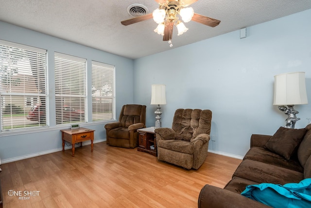 living room with visible vents, a textured ceiling, and light wood-style flooring