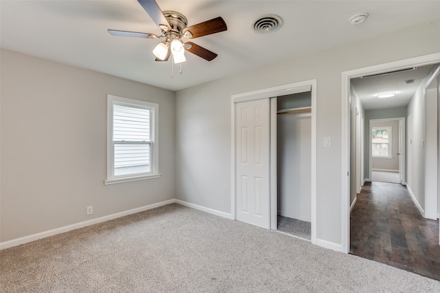 unfurnished bedroom featuring multiple windows, ceiling fan, a closet, and dark carpet