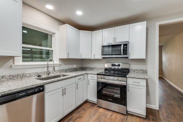 kitchen featuring sink, dark hardwood / wood-style floors, light stone counters, white cabinetry, and stainless steel appliances