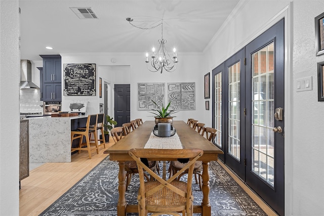 dining area featuring crown molding, light hardwood / wood-style flooring, and a chandelier