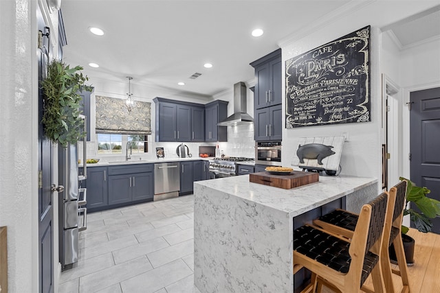 kitchen featuring wall chimney exhaust hood, ornamental molding, appliances with stainless steel finishes, kitchen peninsula, and a breakfast bar area