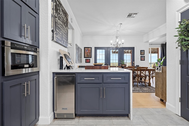 kitchen with gray cabinetry, crown molding, decorative light fixtures, light hardwood / wood-style flooring, and a chandelier