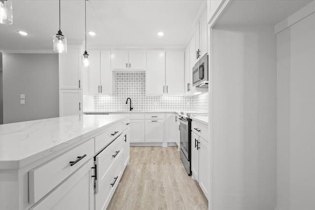 kitchen with hanging light fixtures, light wood-type flooring, appliances with stainless steel finishes, a kitchen island, and white cabinetry