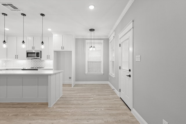 kitchen featuring white cabinetry, ornamental molding, backsplash, pendant lighting, and light wood-type flooring