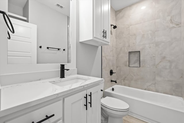 full bathroom with hardwood / wood-style floors, tiled shower / bath combo, toilet, and vanity