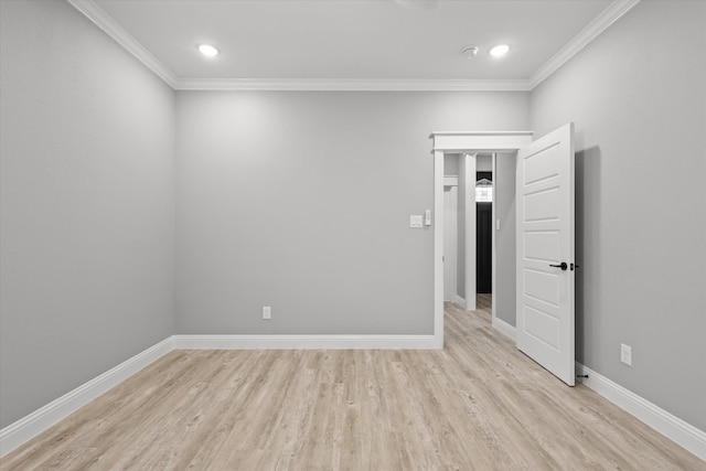 empty room with crown molding and light hardwood / wood-style flooring