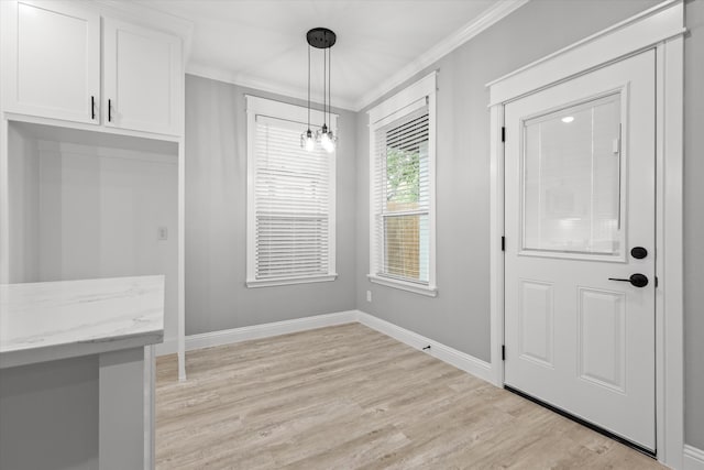 unfurnished dining area featuring a notable chandelier, crown molding, and light hardwood / wood-style flooring