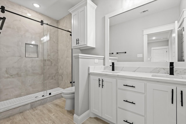 bathroom featuring vanity, hardwood / wood-style flooring, a shower with door, and toilet