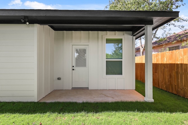 view of exterior entry featuring a lawn and a patio area