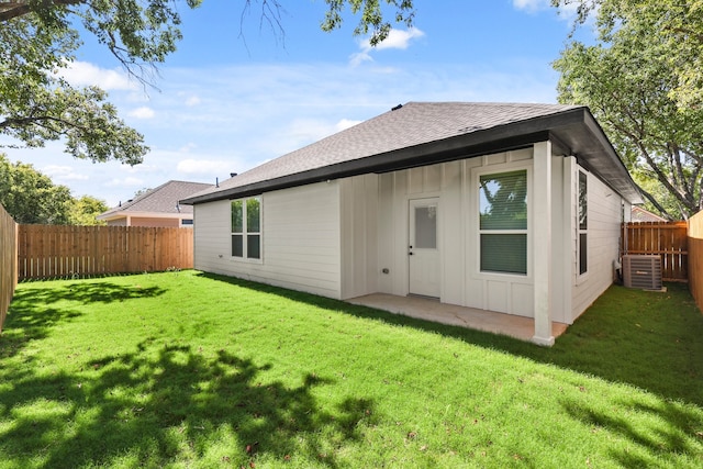 rear view of house featuring central AC unit and a lawn