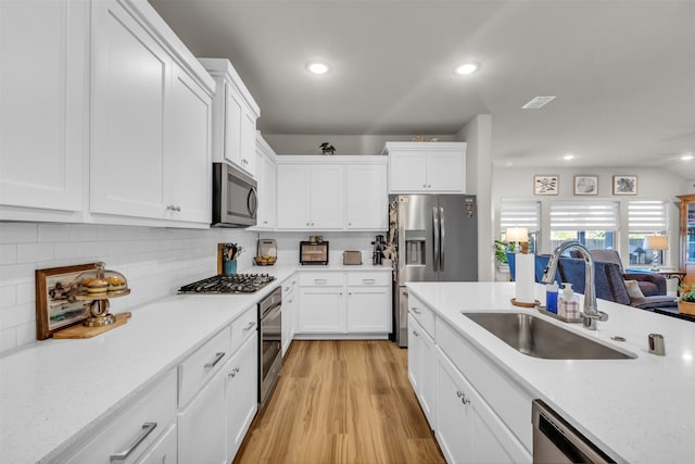 kitchen featuring stainless steel appliances, white cabinetry, light hardwood / wood-style floors, and sink