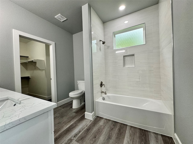 full bathroom with toilet, vanity, tiled shower / bath combo, and hardwood / wood-style flooring