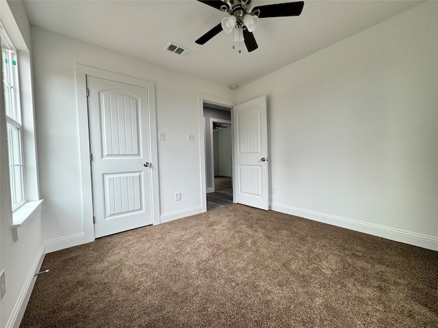 unfurnished bedroom with dark colored carpet and ceiling fan