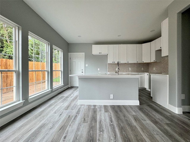 kitchen featuring wood-type flooring, white cabinetry, a kitchen island with sink, and a healthy amount of sunlight